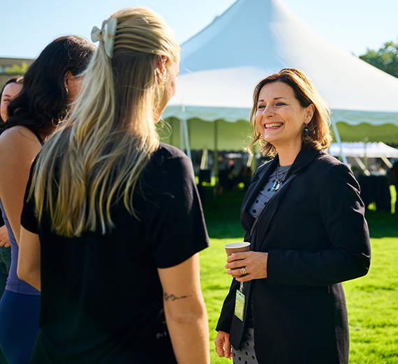 La presidenta Katia Passerini está de pie frente a ventanas en el Centro Hemmingson