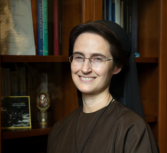 La presidenta Katia Passerini está de pie frente a ventanas en el Centro Hemmingson